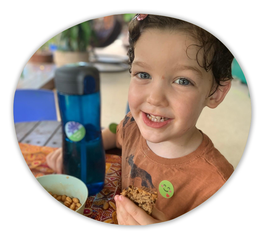 A child smiling while eating lunch.