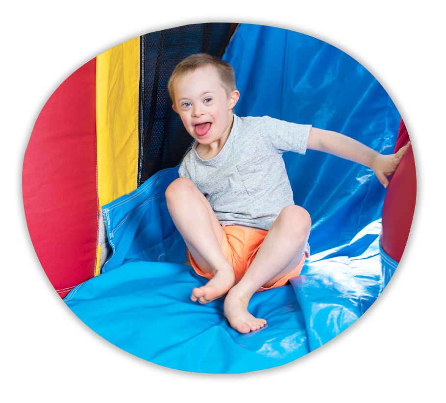 A child smiling as they emerge from the slide of a jumping castle.