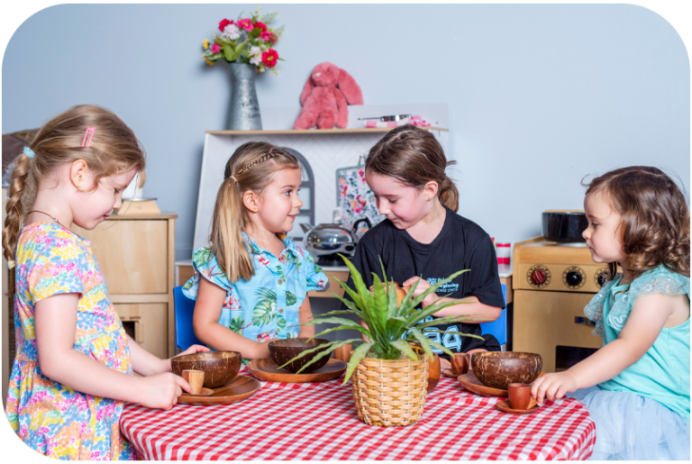 Four children having a tea party party around a table.