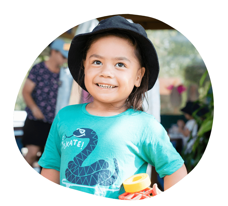 A child smiling as they emerge from the slide of a jumping castle.