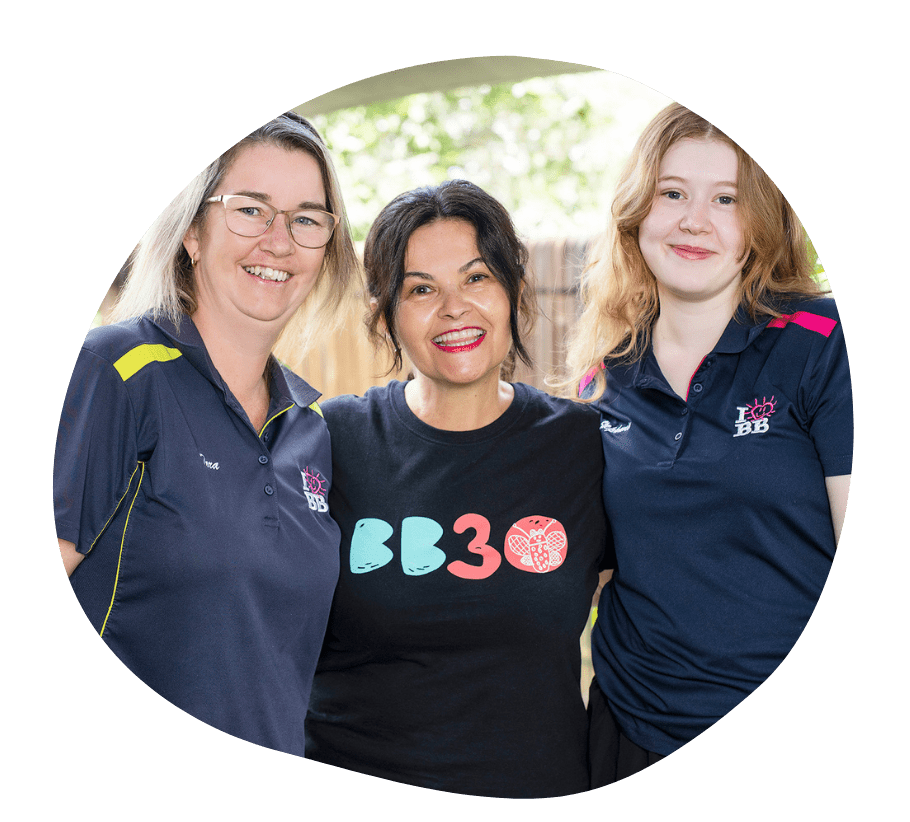 A child sitting on the steps of a cubby house smiling happily.