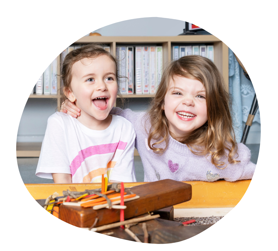 A child in a teal shirt standing in a playground, smiling.