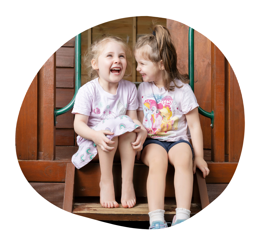 A child in a teal shirt standing in a playground, smiling.
